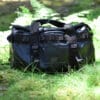 black tarpaulin duffle bag placed in green grass